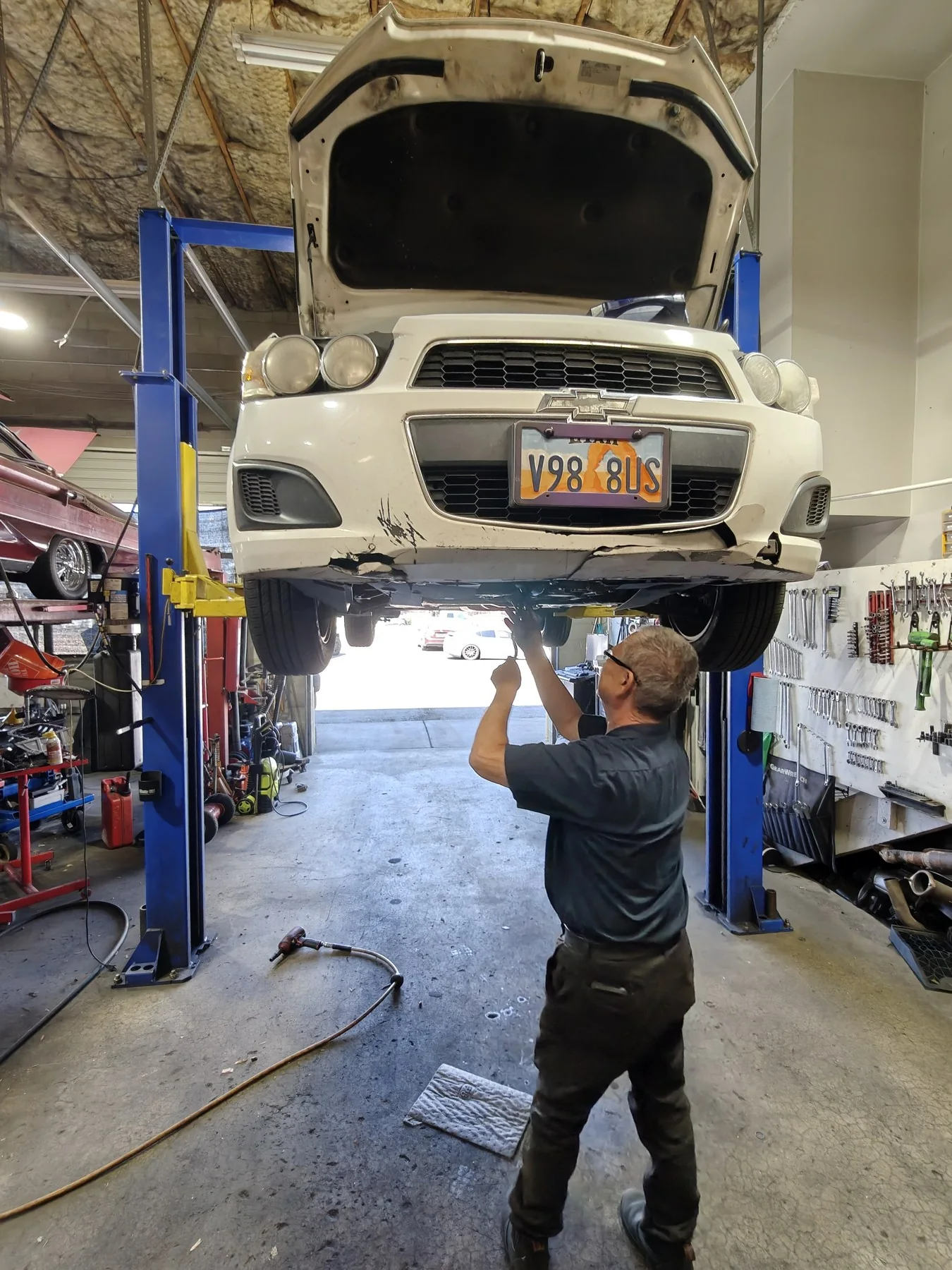 Technician working underneath a vehicle at B3nji's Auto Repair